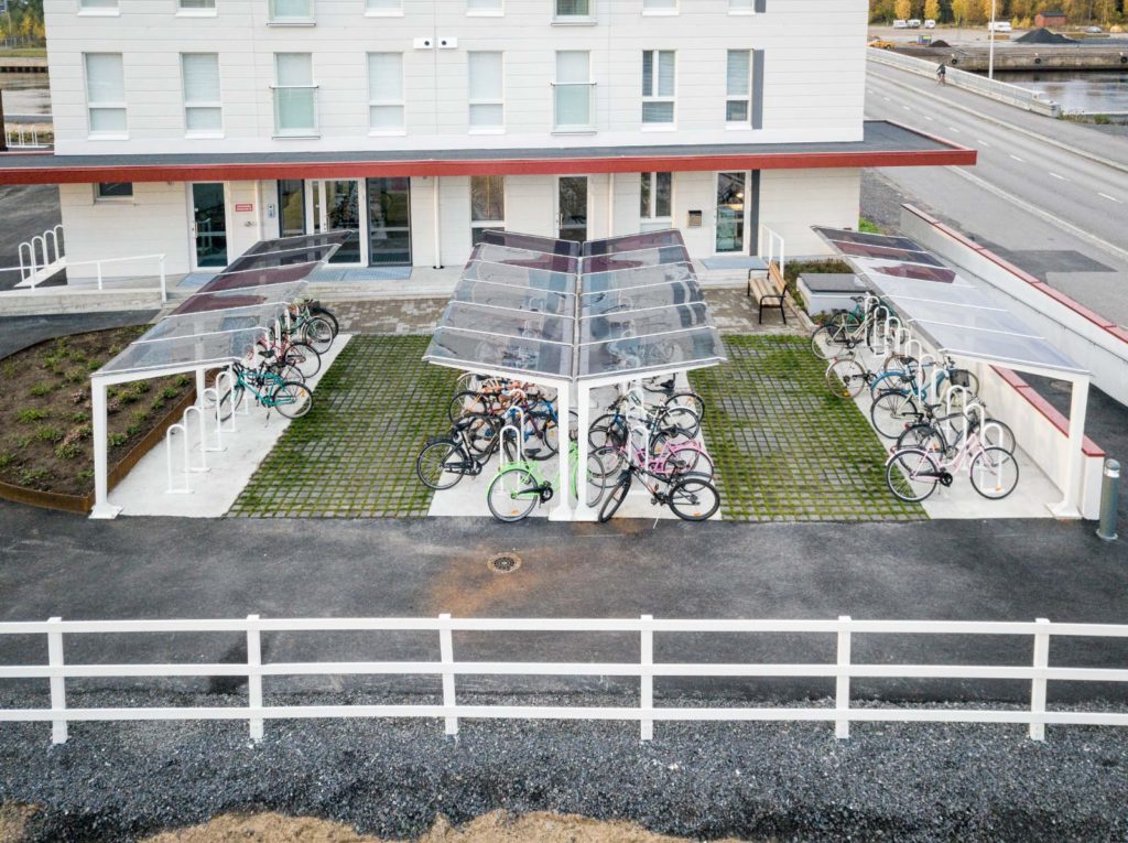 Light pyöräkatos lasin tunteella, neliskulmaiset putket ja katos polykarbonaattia, viimeistely pyöräkatos muotoilullaan, katoksen kanssa voidaan yhdistää runkolukitusteline. Light valkoisilla kattotuilella, kuvan katos Oulusta