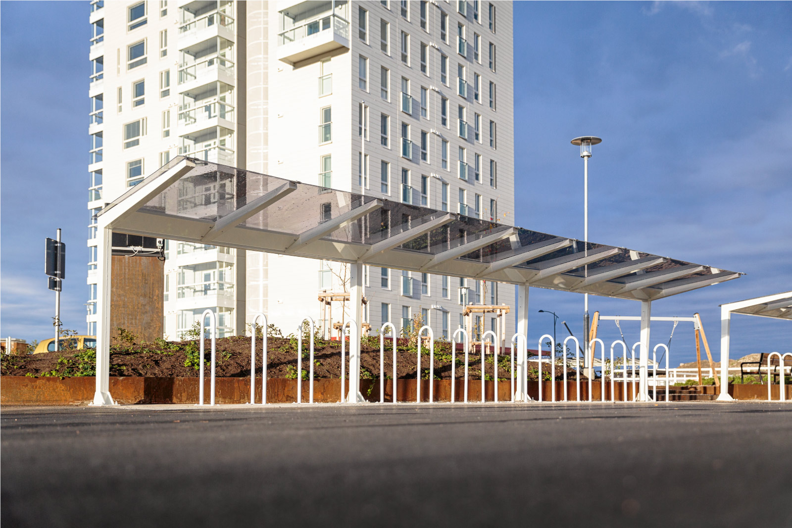 Light pyöräkatos lasin tunteella, neliskulmaiset putket ja katos polykarbonaattia, viimeistely pyöräkatos muotoilullaan, katoksen kanssa voidaan yhdistää runkolukitusteline. Light valkoisilla kattotuilella, kuvan katos Oulusta