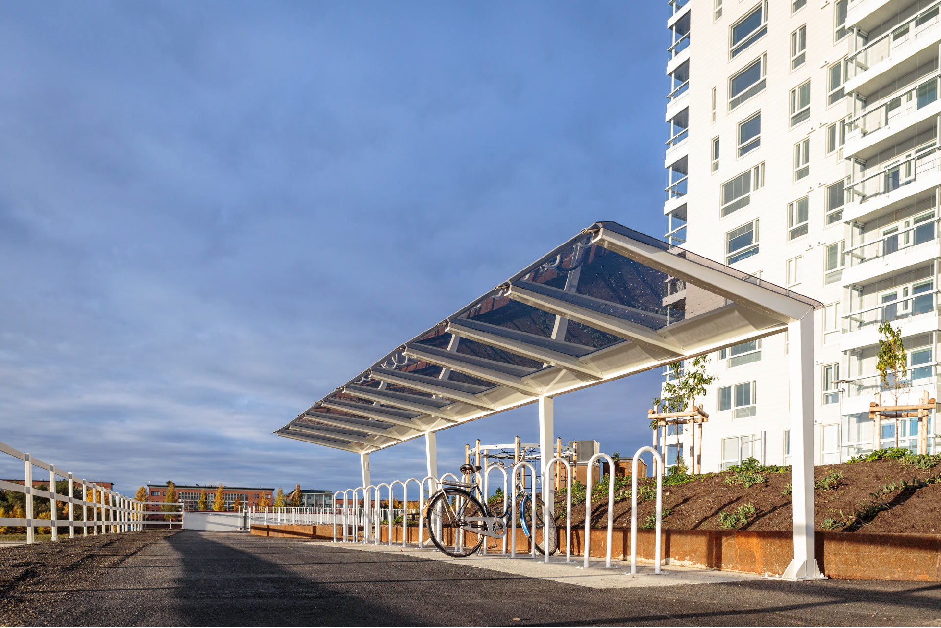 Light pyöräkatos lasin tunteella, neliskulmaiset putket ja katos polykarbonaattia, viimeistely pyöräkatos muotoilullaan, katoksen kanssa voidaan yhdistää runkolukitusteline. Light valkoisilla kattotuilella, kuvan katos Oulusta