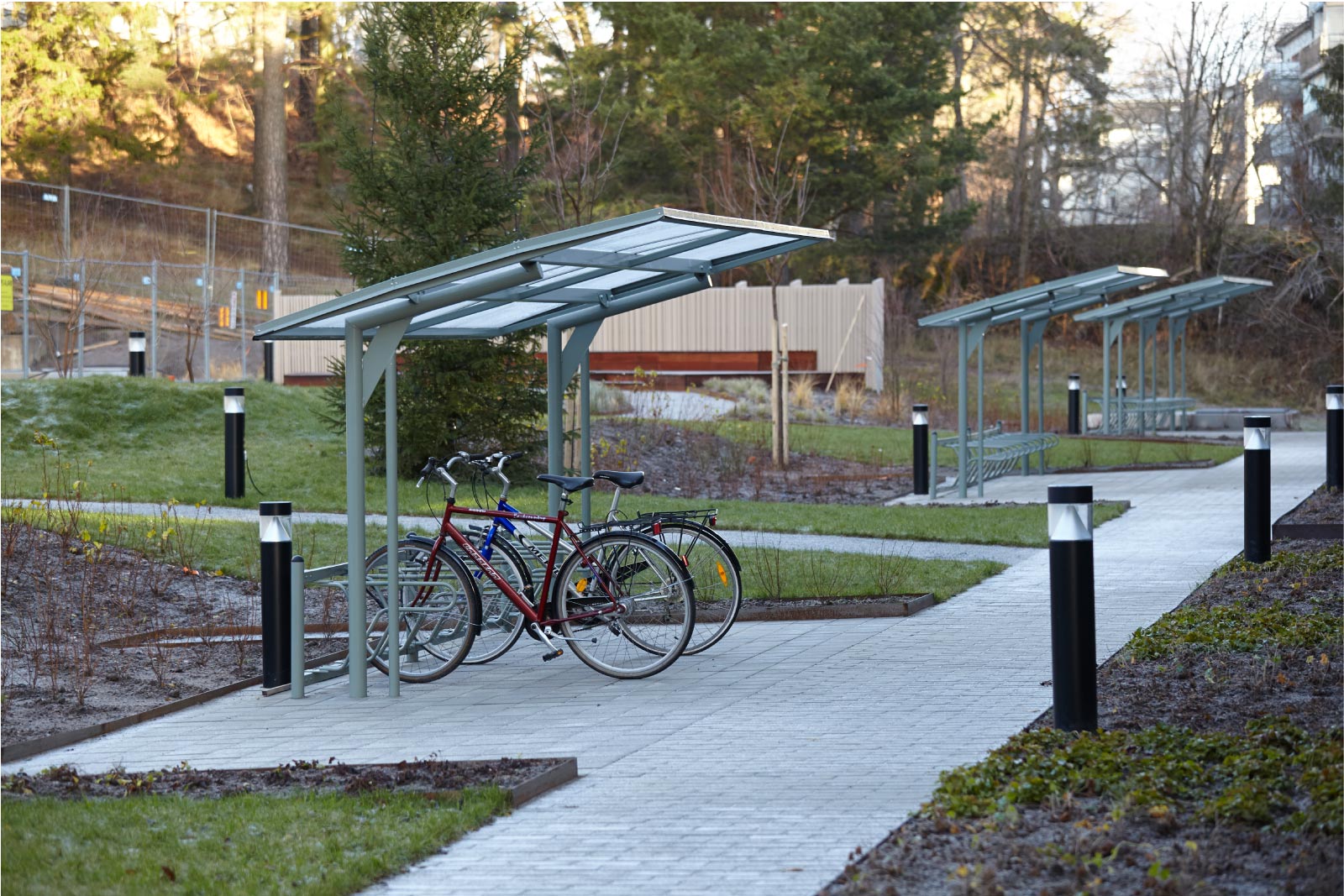 Cyklos KAPPA 5,5 metrin pyöräkatos, ilman päätytolppaa ja Delta runkolukitusteline, pyöräkatos taloyhtiönpihalla