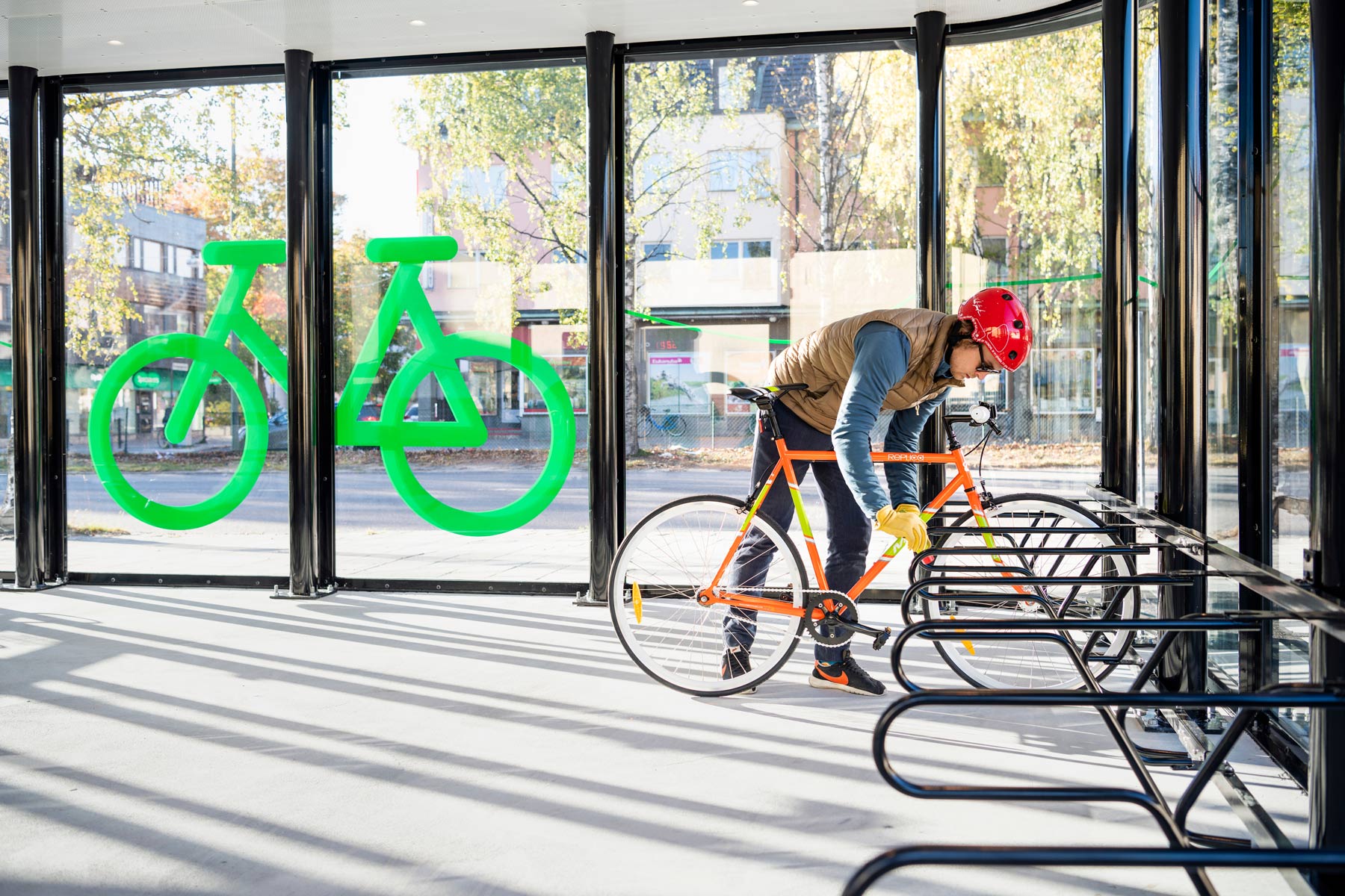 Cykelgarage där en cyklist låser fast en orange cykel i ramen