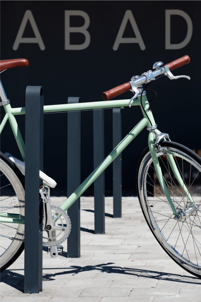 Fyra cykelpollare LUX från Cyklos där det vid en av pollarna står en grön cykel