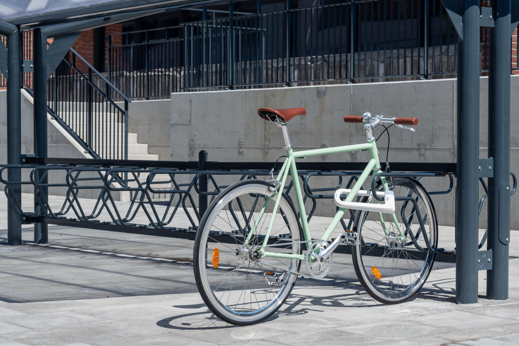 Grön cykel med lädersadel som står i ett svart DELTA cykelställ från Cyklos