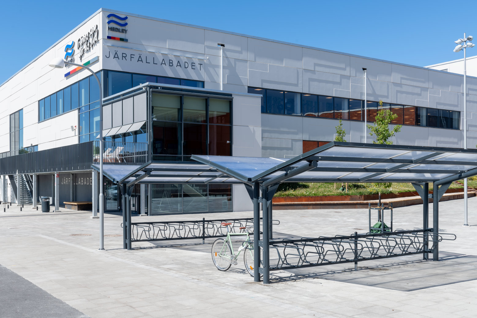 Dubbelsidigt cykeltak YPSILON från Cyklos utanför Järfällabadet i Järfälla tillsammans med cykelställ DELTA där en parkerad cykel är fastlåst i ramen