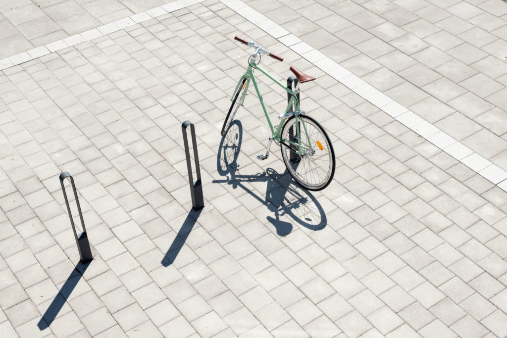 Tre cykelpollare LUX från Cyklos där det vid en av pollarna står en grön cykel