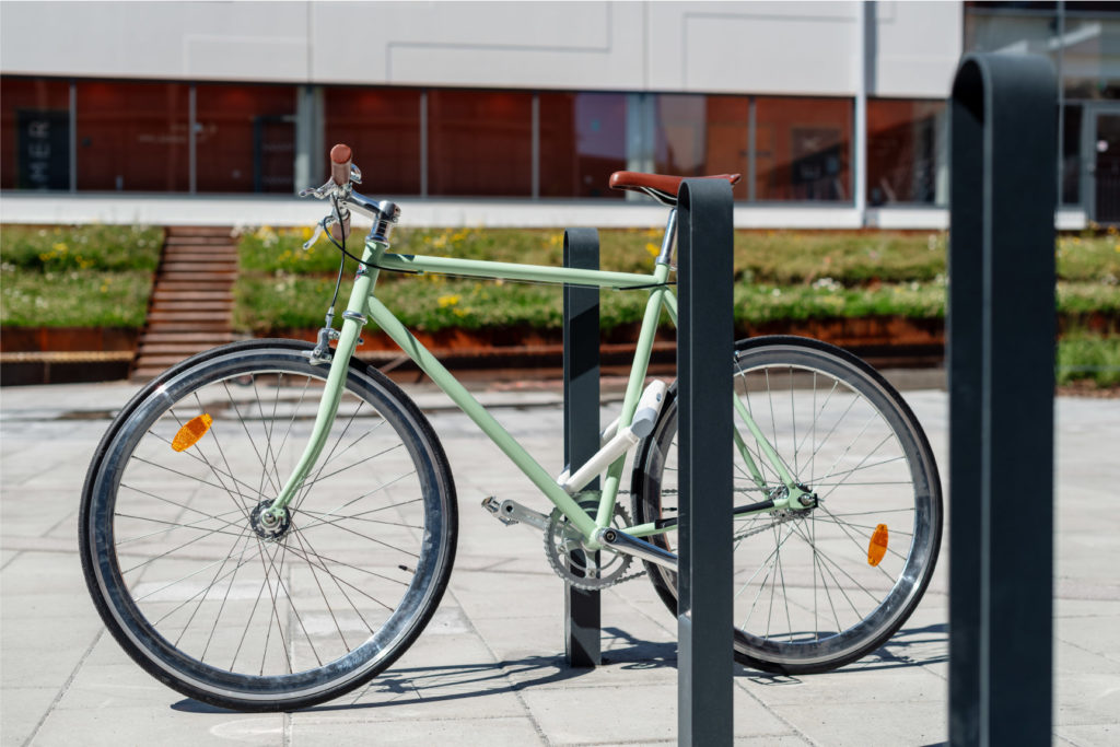 Tre cykelpollare LUX från Cyklos där det vid en av pollarna står en grön cykel