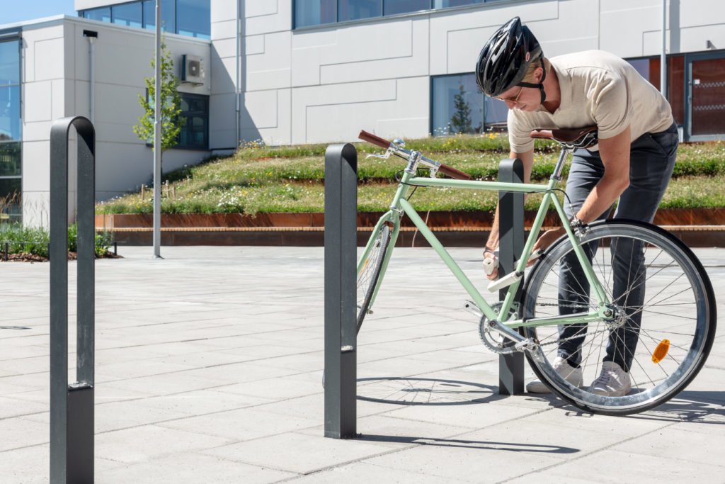 Cyklist låser fast en grön cykel vid en cykelpollare LUX från Cyklos