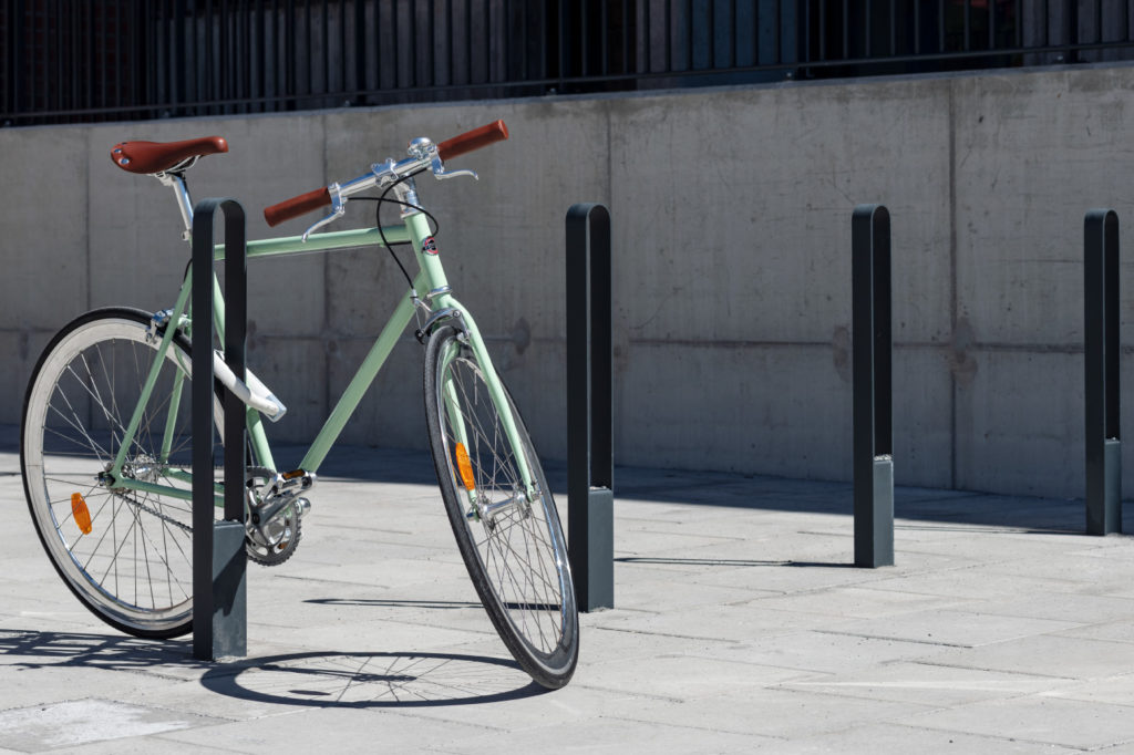 Fyra cykelpollare LUX från Cyklos där det vid en av pollarna står en grön cykel
