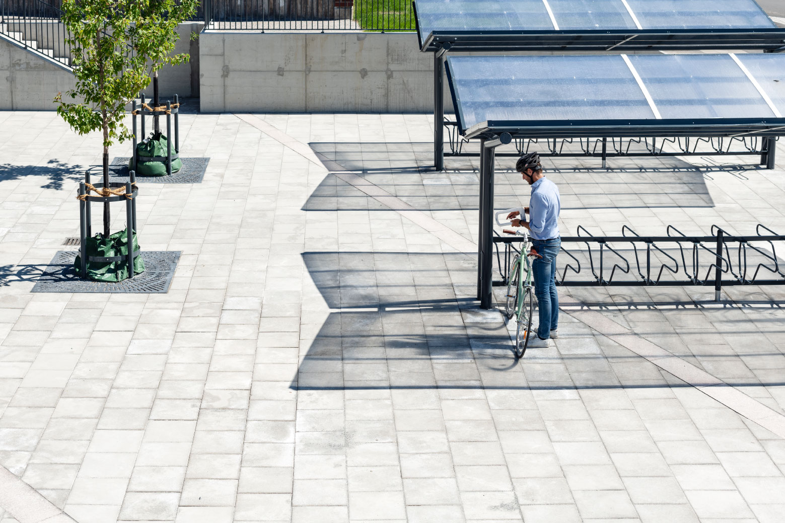 En cyklist låser sin cykel i det dubbelsidiga cykelstället DELTA under det dubbelsidiga cykeltaket YPSILON från Cyklos