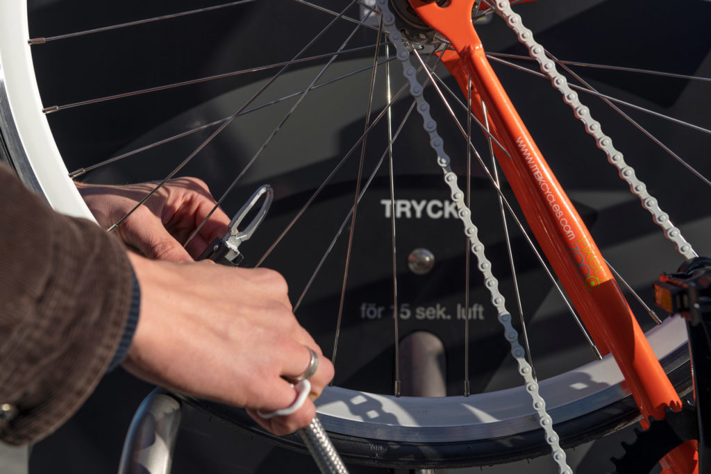 Cyklist fäster pumpmunstycket för att pumpa cykeln på cykelservicestationen GRAND från Cyklos
