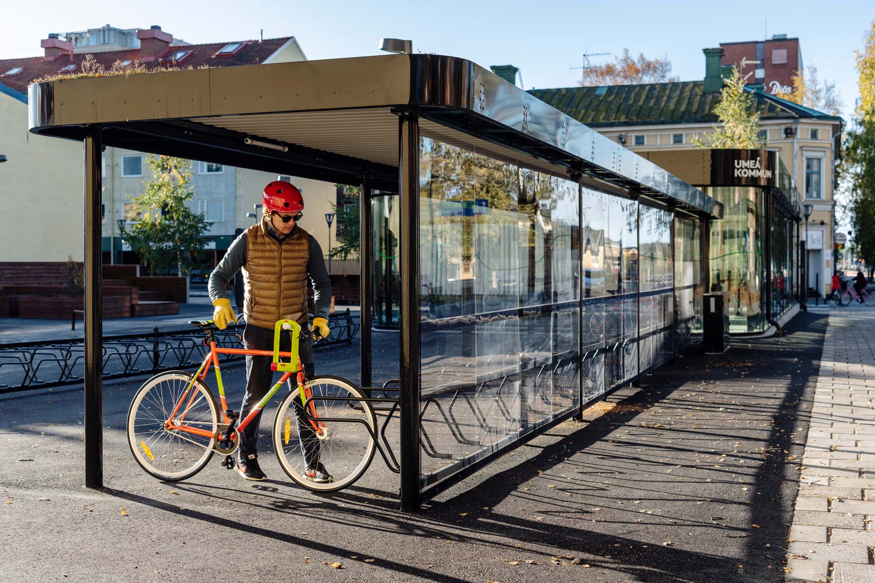 Cykeltak och cykelställ där cyklist parkerar sin rödgröna cykel