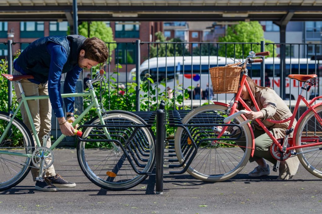 Cykelställ där två cyklister låser fast cykeln i ramen