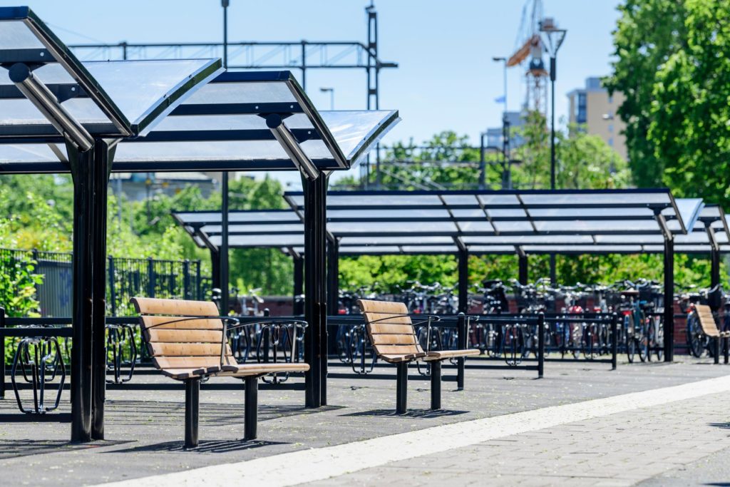 Dubbelsidigt cykeltak från Cyklos med parkbänkar framför.