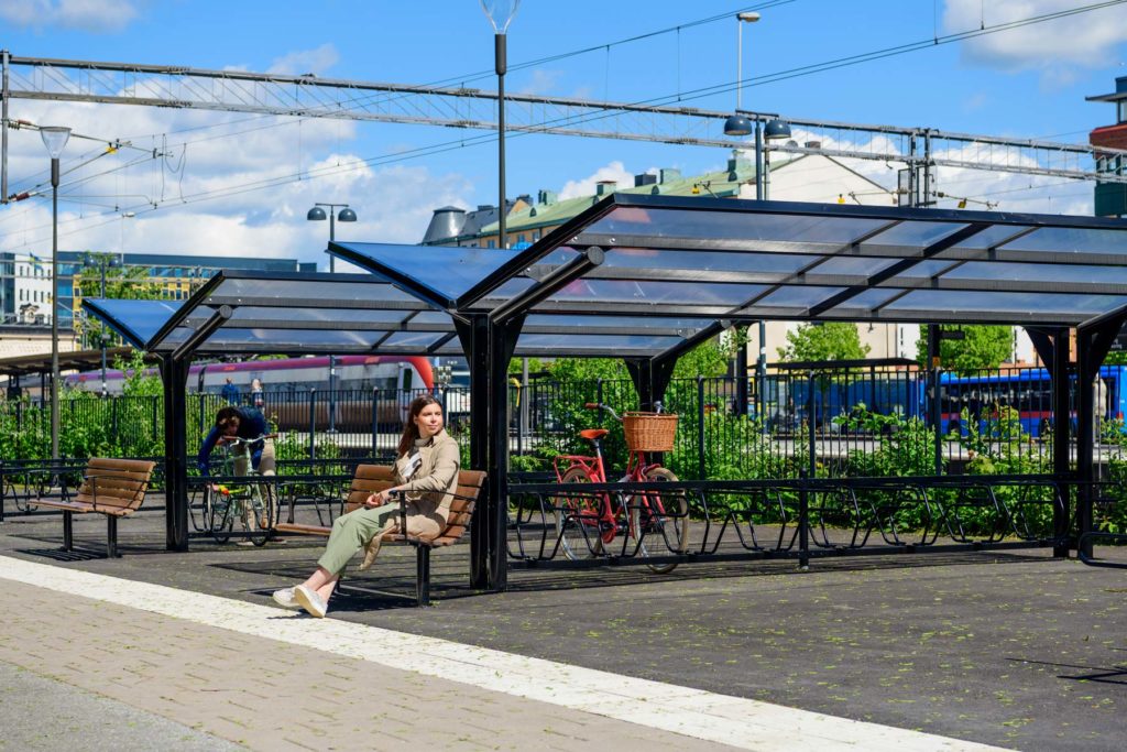 Cykeltak i dubbelt utförande och en parkbänk där en kvinna sitter.
