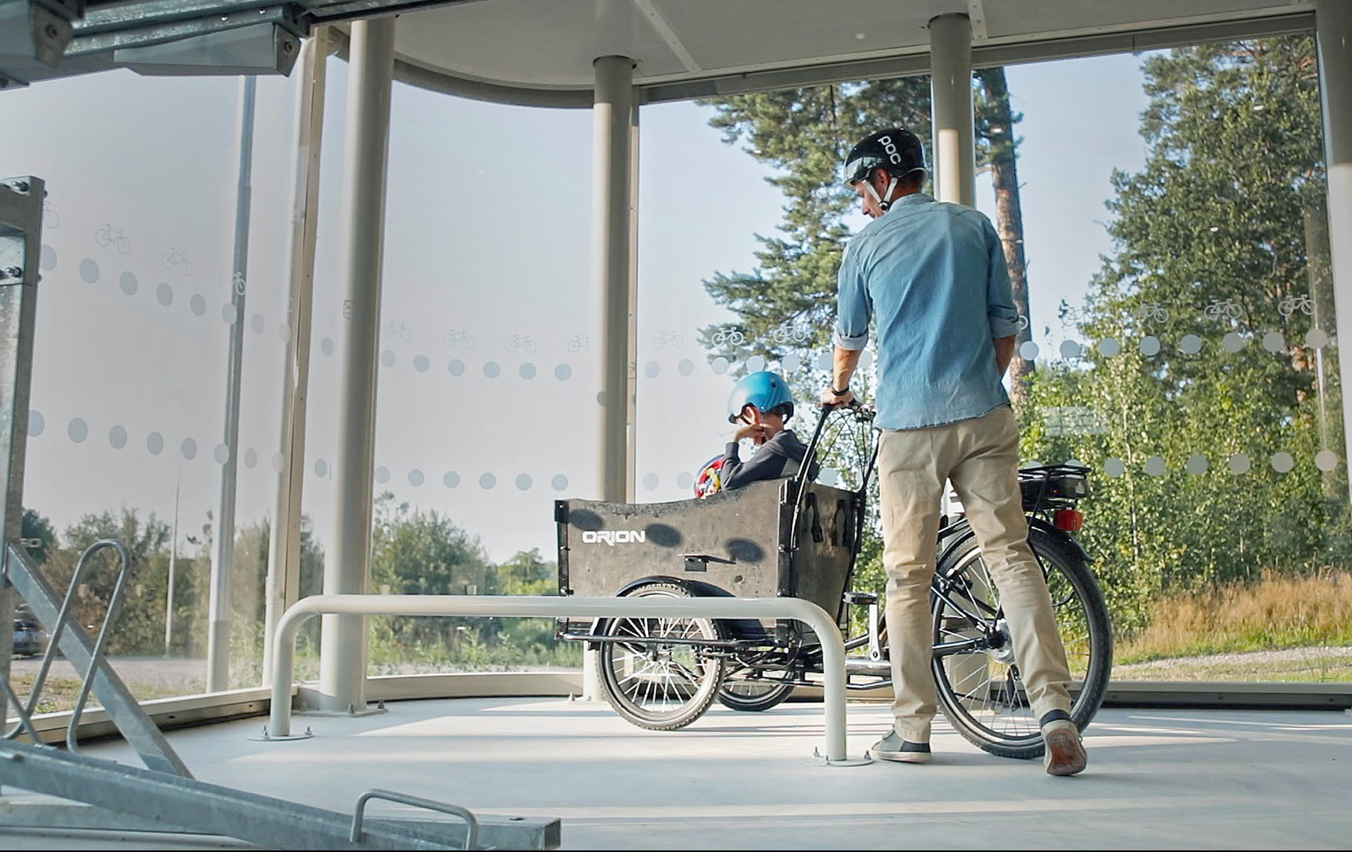 En pappa parkerar sin lastcykel vid en cykelparkering