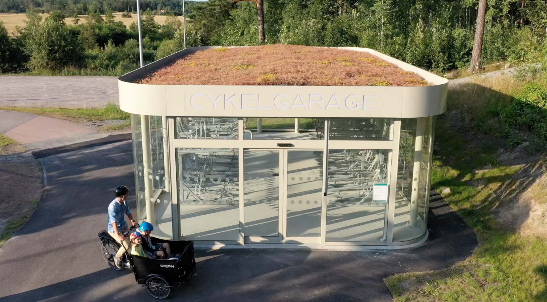 Cykelgarage och en pappa på lådcykel som skjutsar två barn